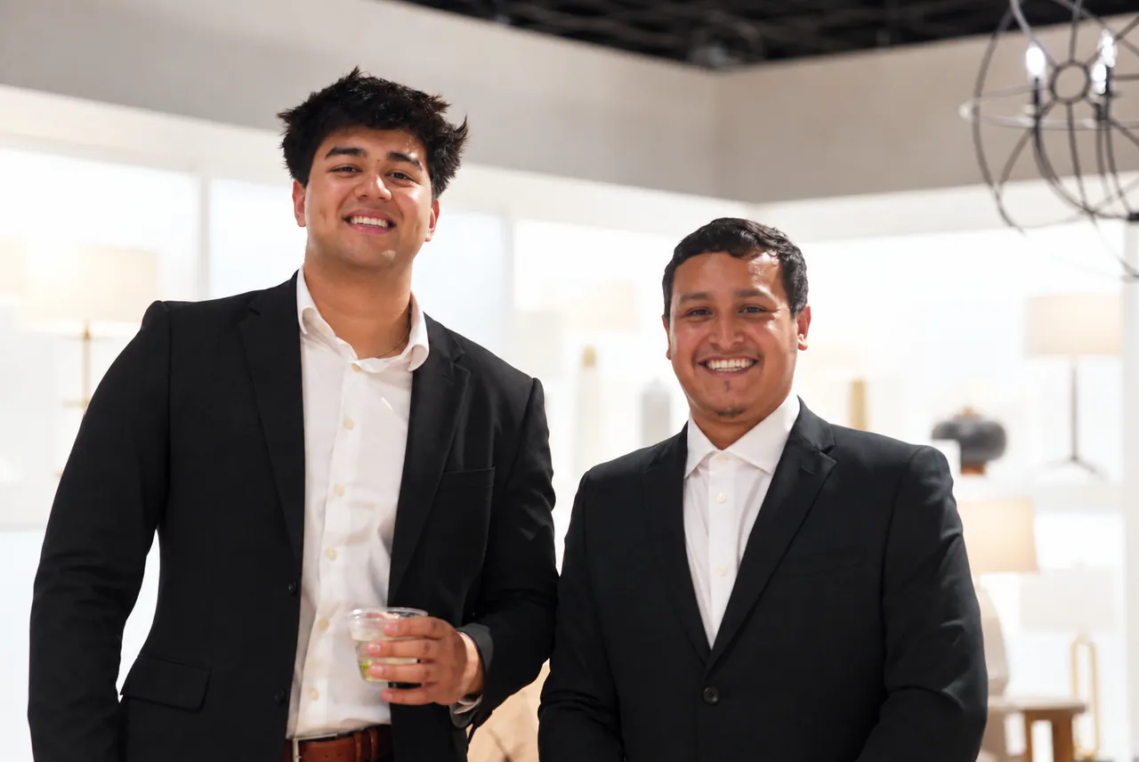 Two guests with drinks under the showroom chandeliers